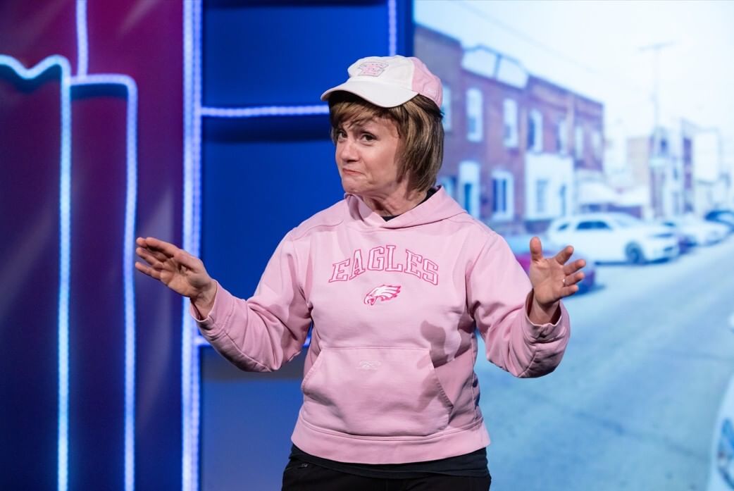 Closeup on Childs, a white woman with short blonde hair, wearing a pink Philadelphia Eagles hoodie and hat.
