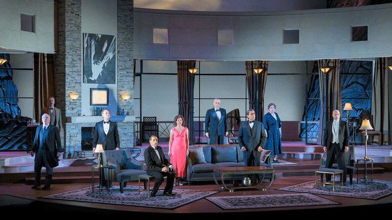 On a spacious mid-century modern set with huge windows, nine actors in formal wear pose with dramatic grace.