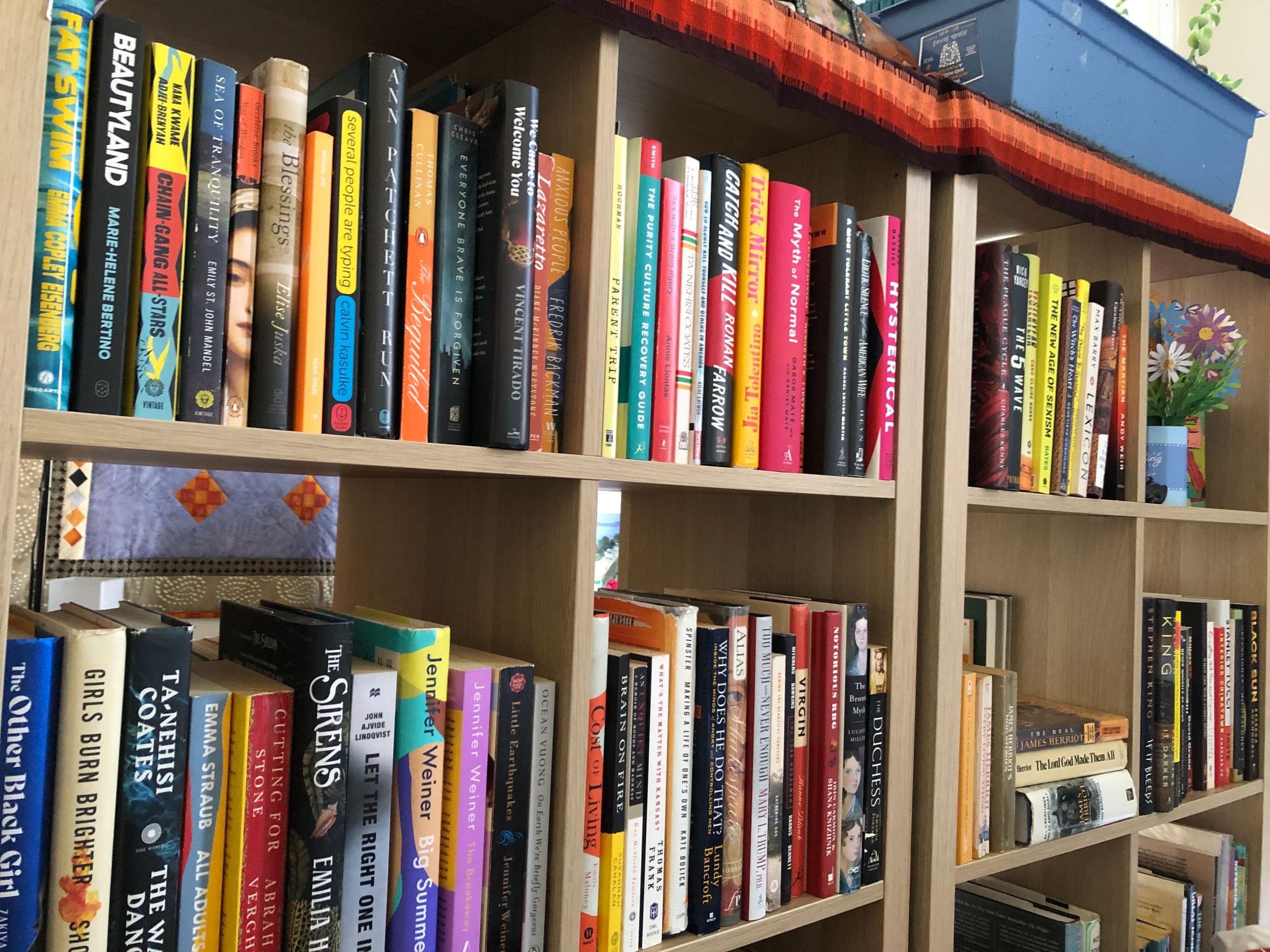 Close-up view of light wooden shelves in square cubbies jammed with colorful books.