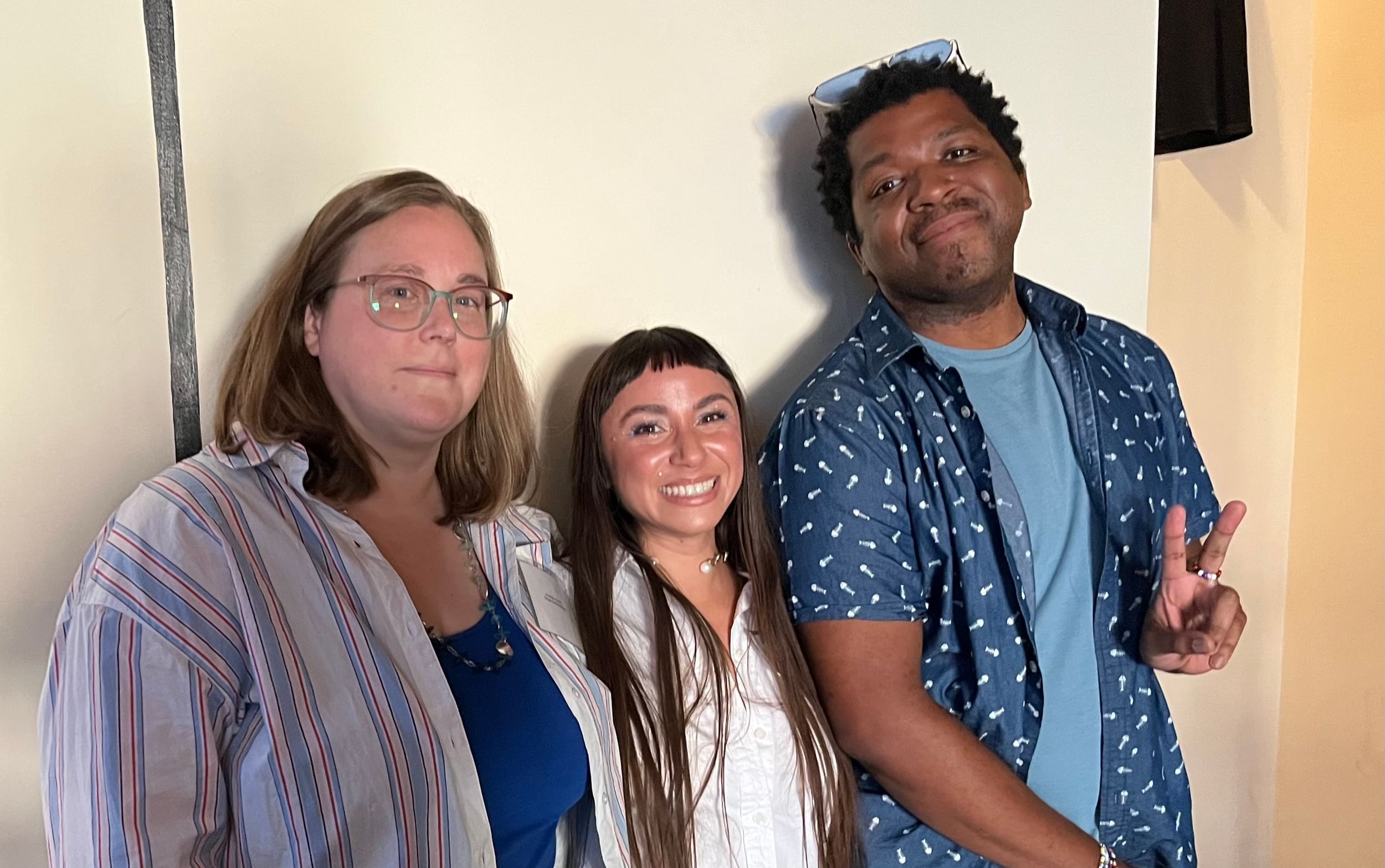 Alaina, a white woman, Vicky, a Latina woman, and Kyle, a Black man, pose together smiling in casual clothes.