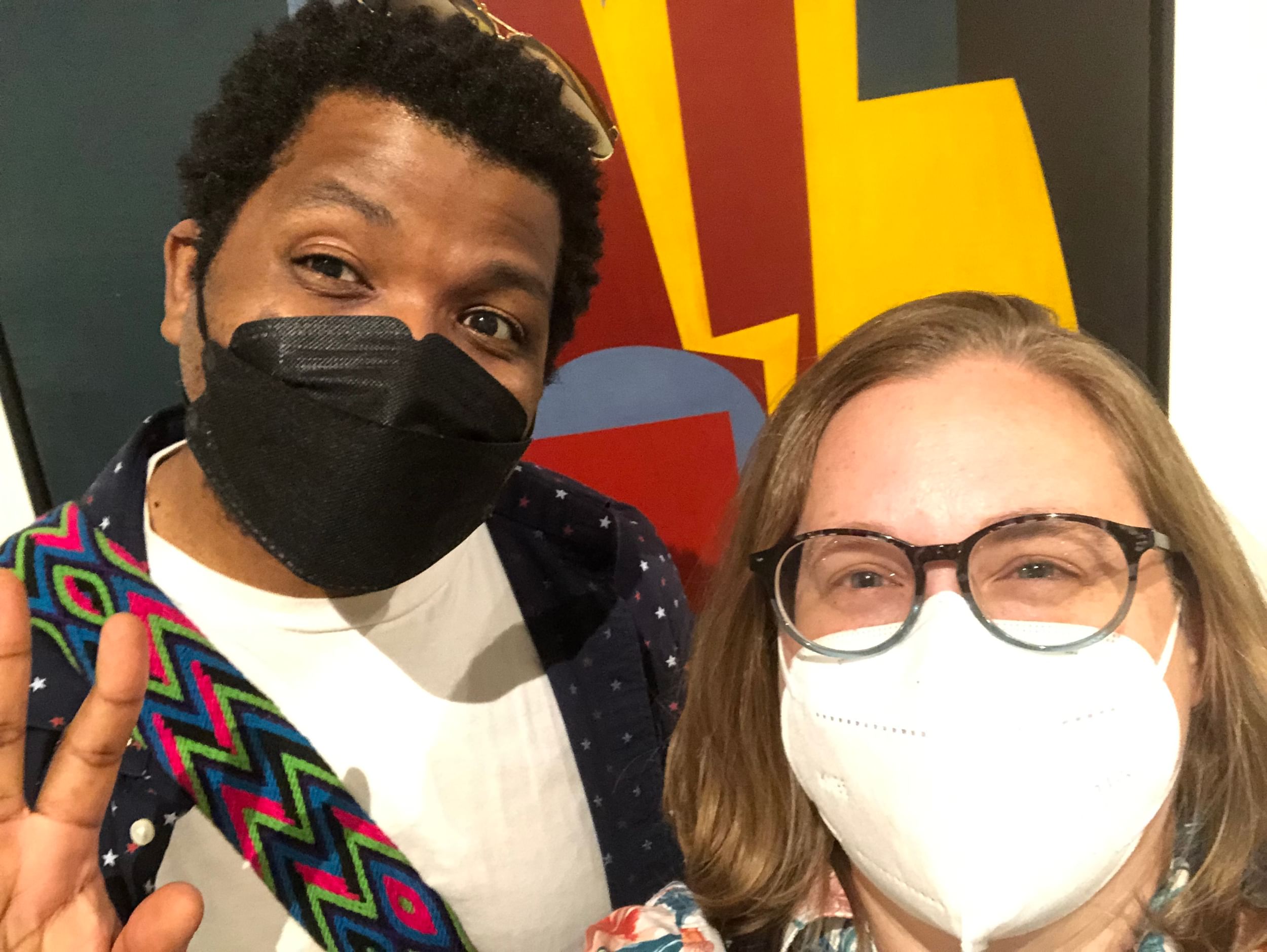 Kyle, a Black man with a black mask, and Alaina, a white woman with a white mask and glasses, smile