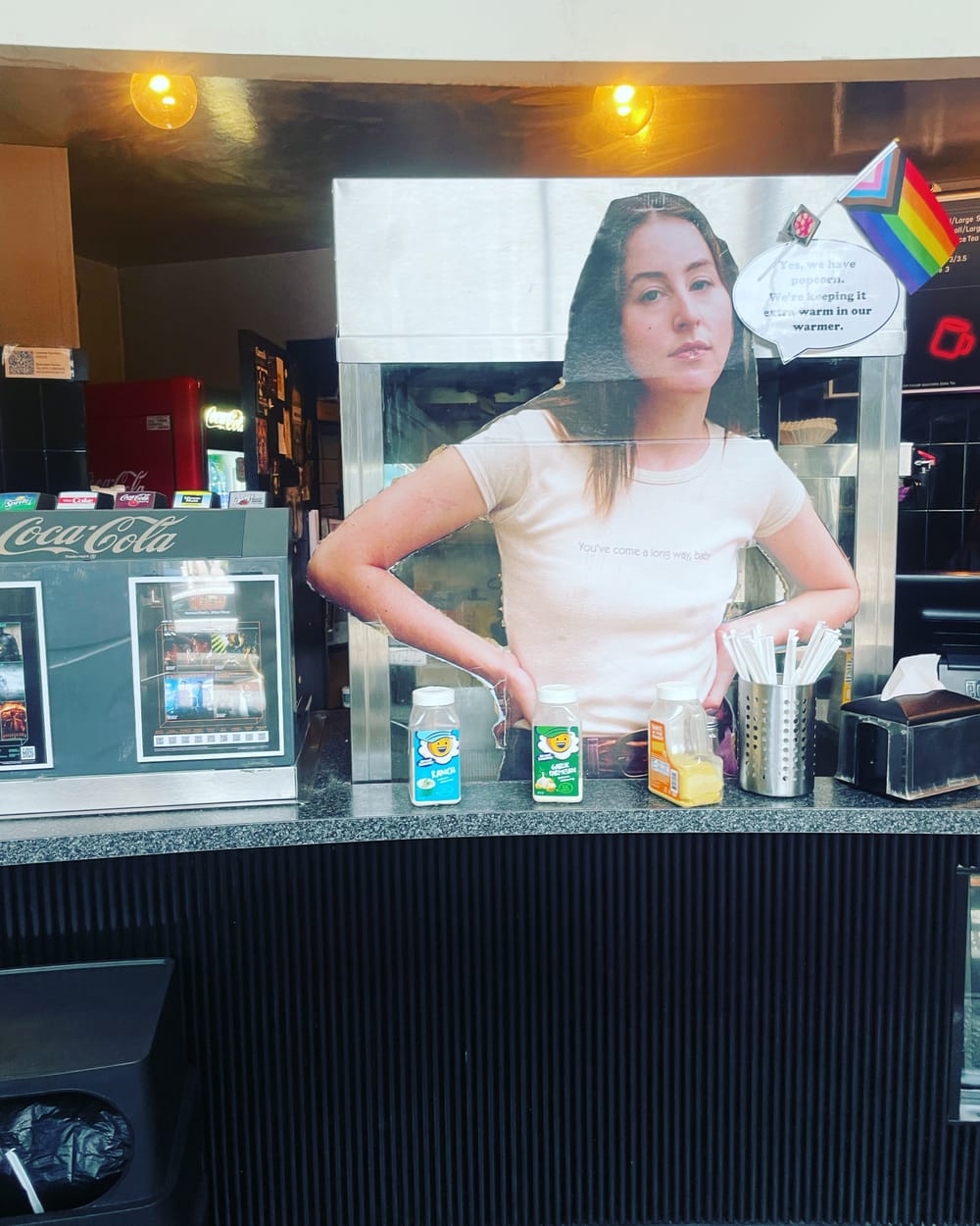 Alana Haim in ‘Licorice Pizza’ as a cardboard cutout at a movie theater concession and ticket stand