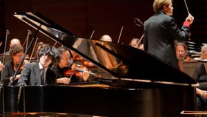 Lim passionately plays a grand piano with his hair flying; Alsop is seen from behind at right, conducting the orchestra