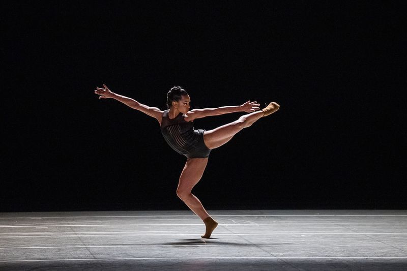 In brown socks and black leotard, Veiga poses on one bent, muscular leg while extending every other limb.