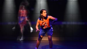 Khalil, in blue & orange basketball uniform, mimes dribbling the ball, a blurry wall projection of another player behind her