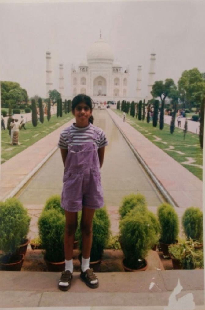 Indian American writer Christina Anthony as a child, pictured in front of the Taj Mahal. She wears purple overalls