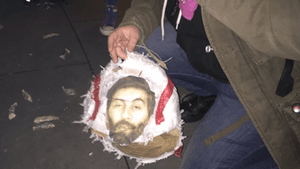 An Antifa Philadelphia member holds what's left of a piñata depicting "manosphere" guru Roosh V. (Photo via @PhillyAntifa/Twitter)