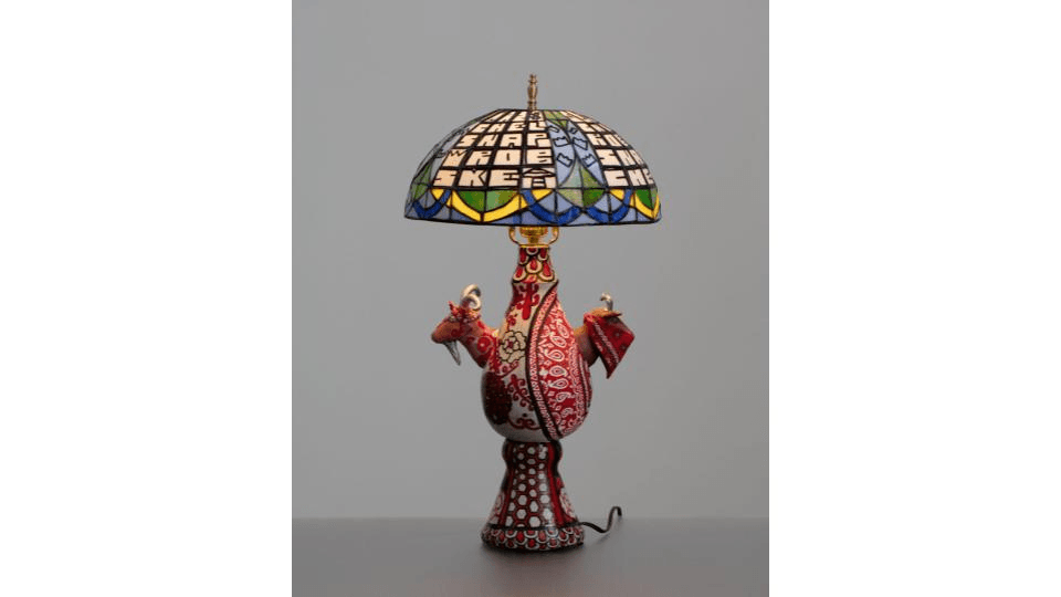 Tiffany-style stained glass lamp with a ceramic base patterned like a red handkerchief with 2 small goat heads mounted on it