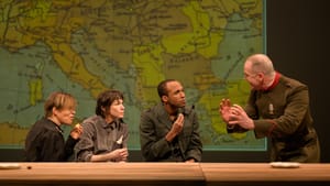 In front of a huge vintage European map, Hulom, Gliko & Pierce look intently toward Rishard, who’s explaining something.