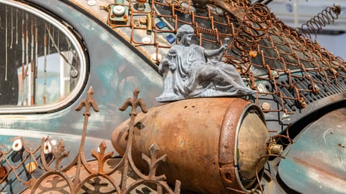 Close-up on Art Car, described in the piece below. A miniature classical-style statue perches on an old Beetle tail-light.