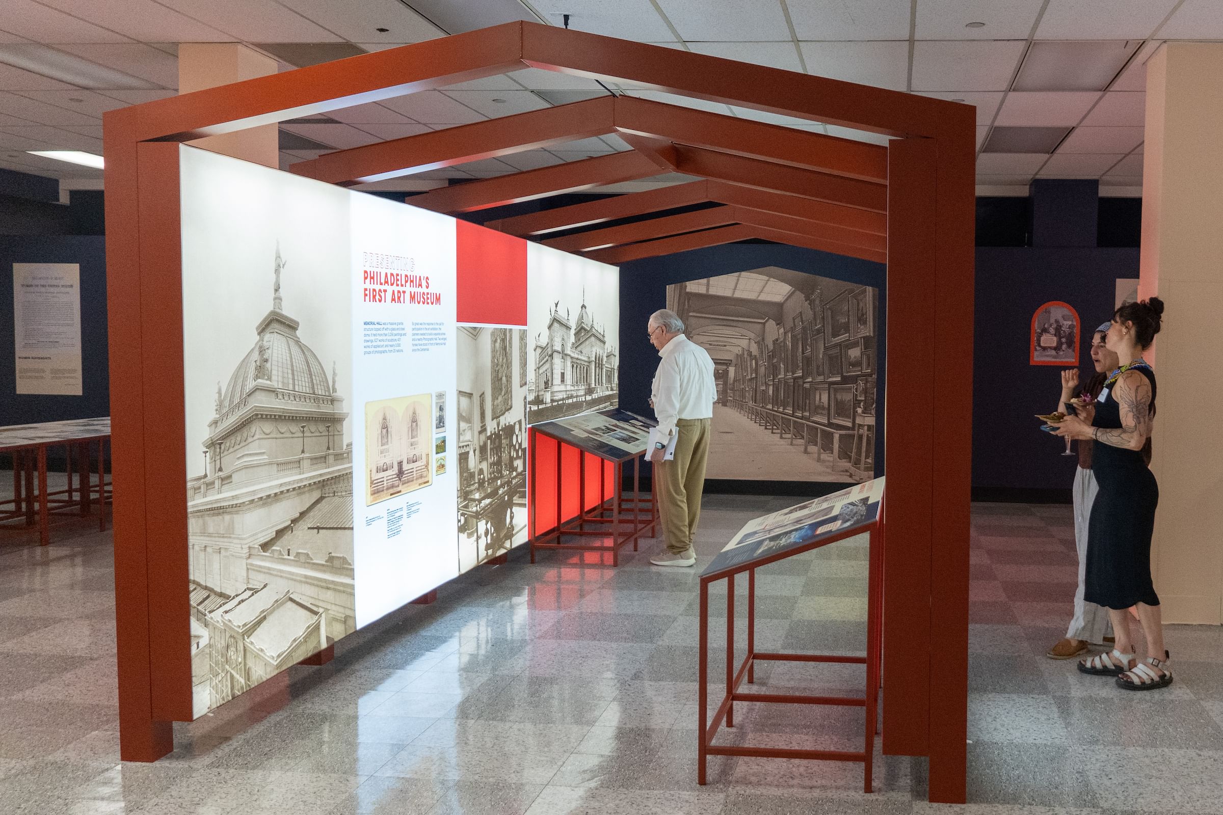 In a gray checkerboard marble-floor gallery, a red structure houses an exhibit on Philly’s first art museum.