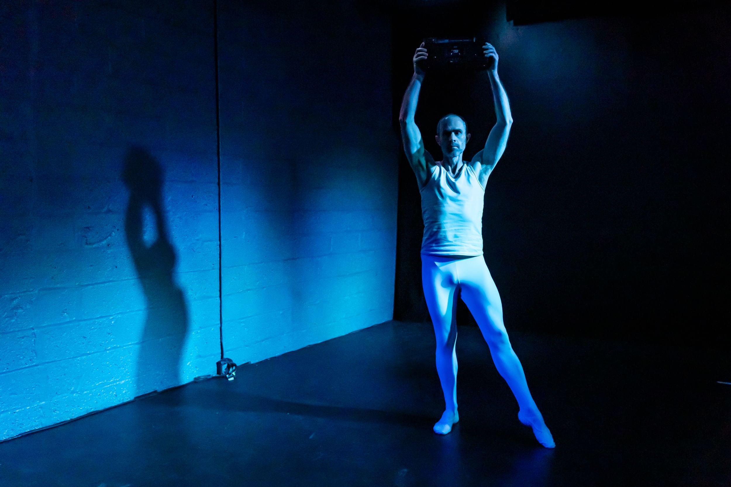 In a blue wash of light, Davis wears white tights, pointing one foot while solemnly holding a boombox aloft.