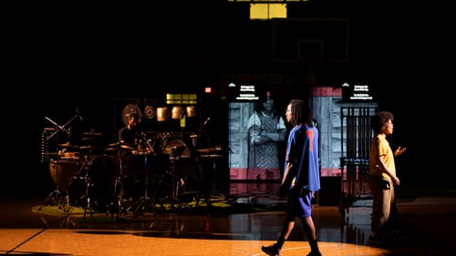 Gay on stage in a vintage Sixers jumpsuit, percussion behind him, a projection of the book cover, and Wisher to the right