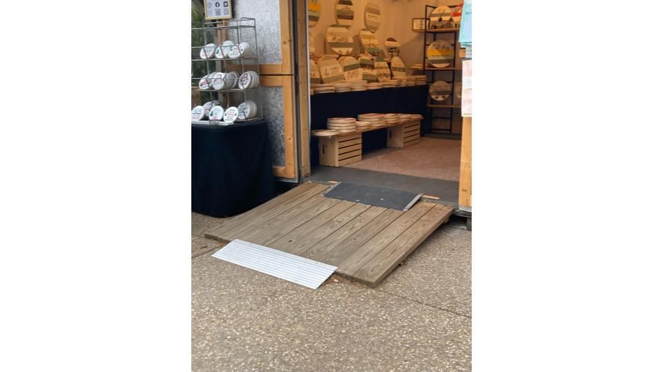 Close-up on a sturdy wooden ramp going into a small outdoor shop selling home décor.