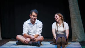 Howard and Kuerzi, in white collared shirts, sit next to each other smiling on a low wooden platform.