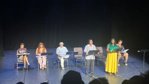 Espinoza and Miller-White, reading scripts on music stands, stand in front of four other Black cast members seated behind.