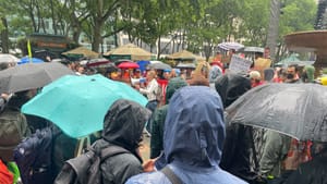 Nixon speaks into a megaphone in the center of a large crowd of people with slickers and umbrellas in the pouring rain.