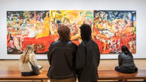 Four people with their backs to the camera look intently at Brown’s large, colorful abstract triptych painting at the Barnes.