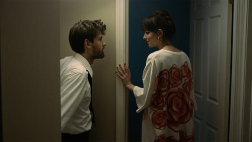 Scene from the film: A young man in shirt & tie beside a woman in long t-shirt stopping at what looks like a bedroom door.