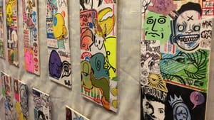 A wall of collages of sticker art on elevated canvas boards