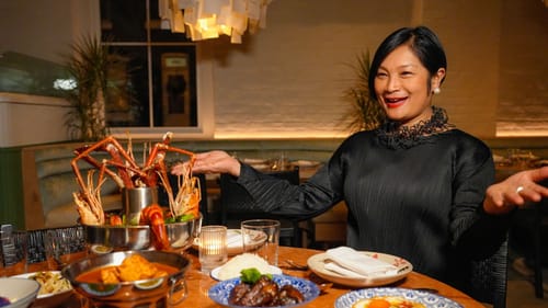 Chef Nok, in a stylish black blouse, smiles and proudly presents a table full of her signature Kalaya dishes.