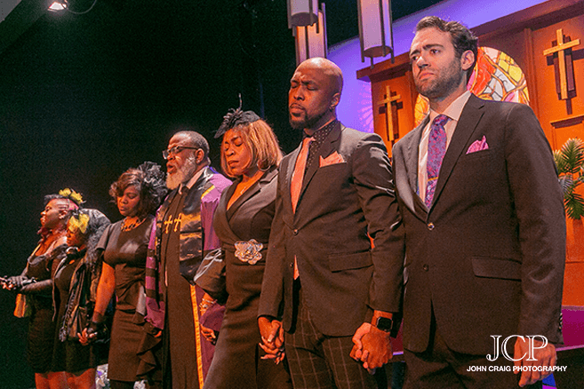 Seven cast members, in funeral black, stand somberly in the line with their hands joined on a stage designed like a chancel.