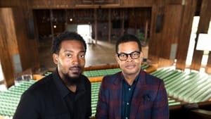 Chill Moody and Atwater dress in mostly black, pose at the balcony of the Mann, the lower level behind them