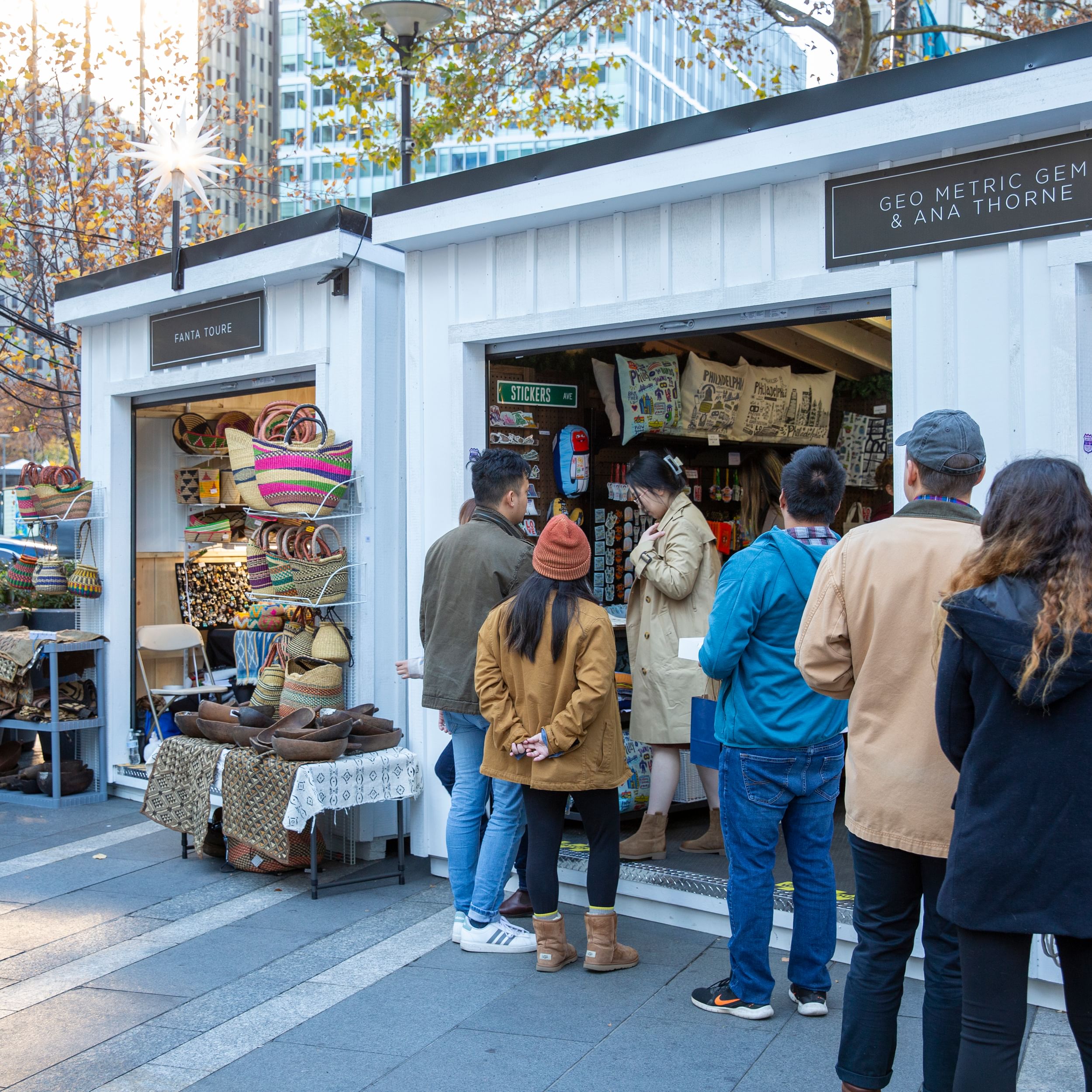 Daytime view of two white outdoor holiday shopping booths that require people to step up into them.