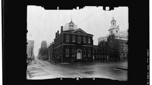 Vintage black & white photo of the historic brick buildings with wide, wet, empty streets around them.