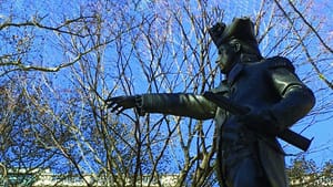 A side-view from below of the Commodore Barry statue on what looks like a sunny winter day.