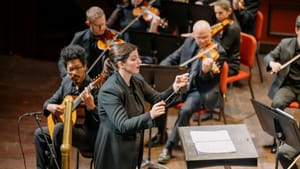 Di Russo, an Argentinian conductor wearing a black suit with long tails, conducts the players around her with a thin baton.