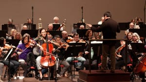 An unusual ongoing dialogue: Cellist Camille Thomas, Maestro David Amado, and the orchestra in rehearsal for DSO’s ‘False Starts’ program. (Photo Courtesy of Delaware Symphony Orchestra.)