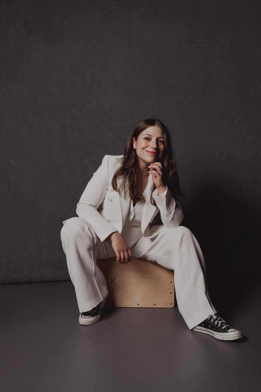 Stasevska in an all-white suit with jacket and black and white Chucks poses for a portrait style photo