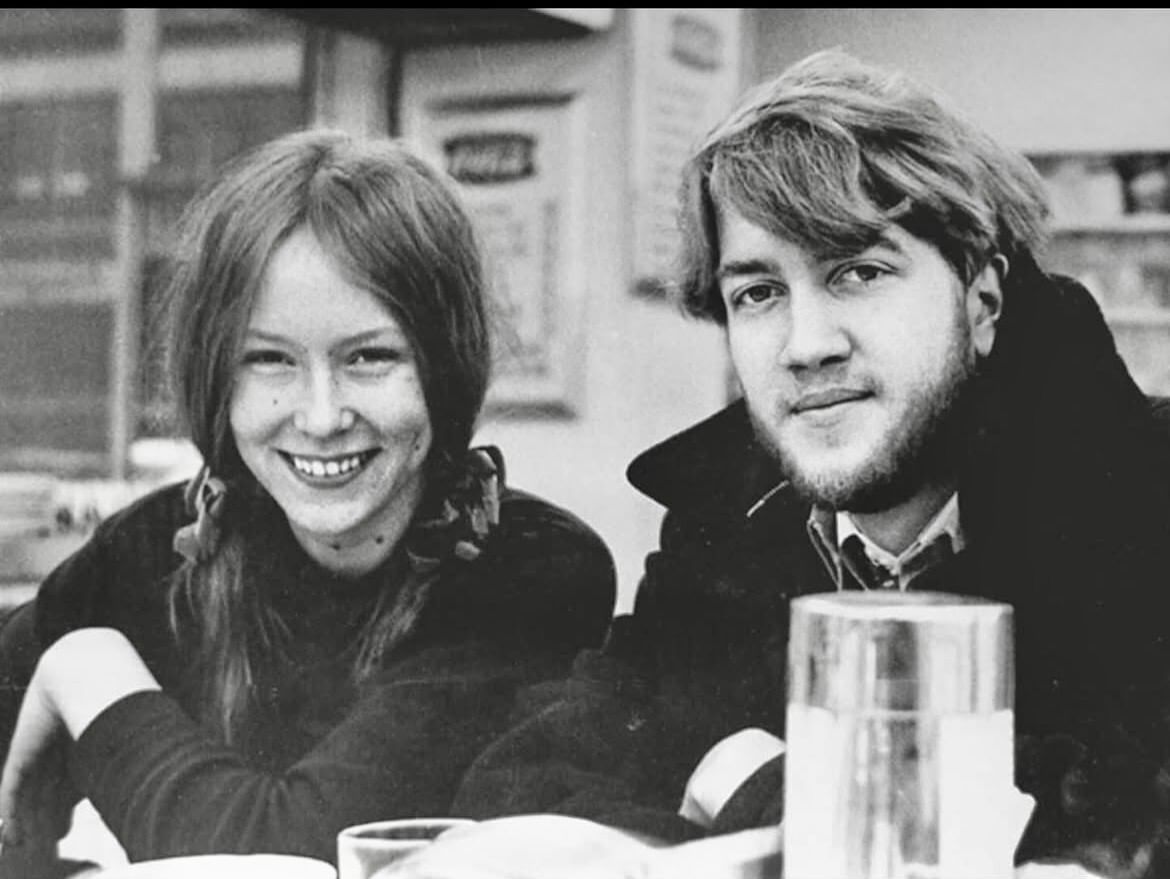 Lynch and Reavey look on in a black and white snapshot, windows and signage in the cafeteria backdrop
