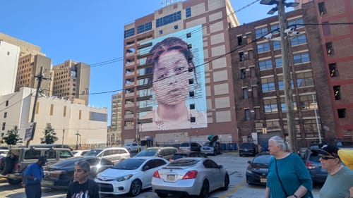 9-story portrait of a young woman’s unimpressed face with the text of the Declaration of Independence superimposed over it.
