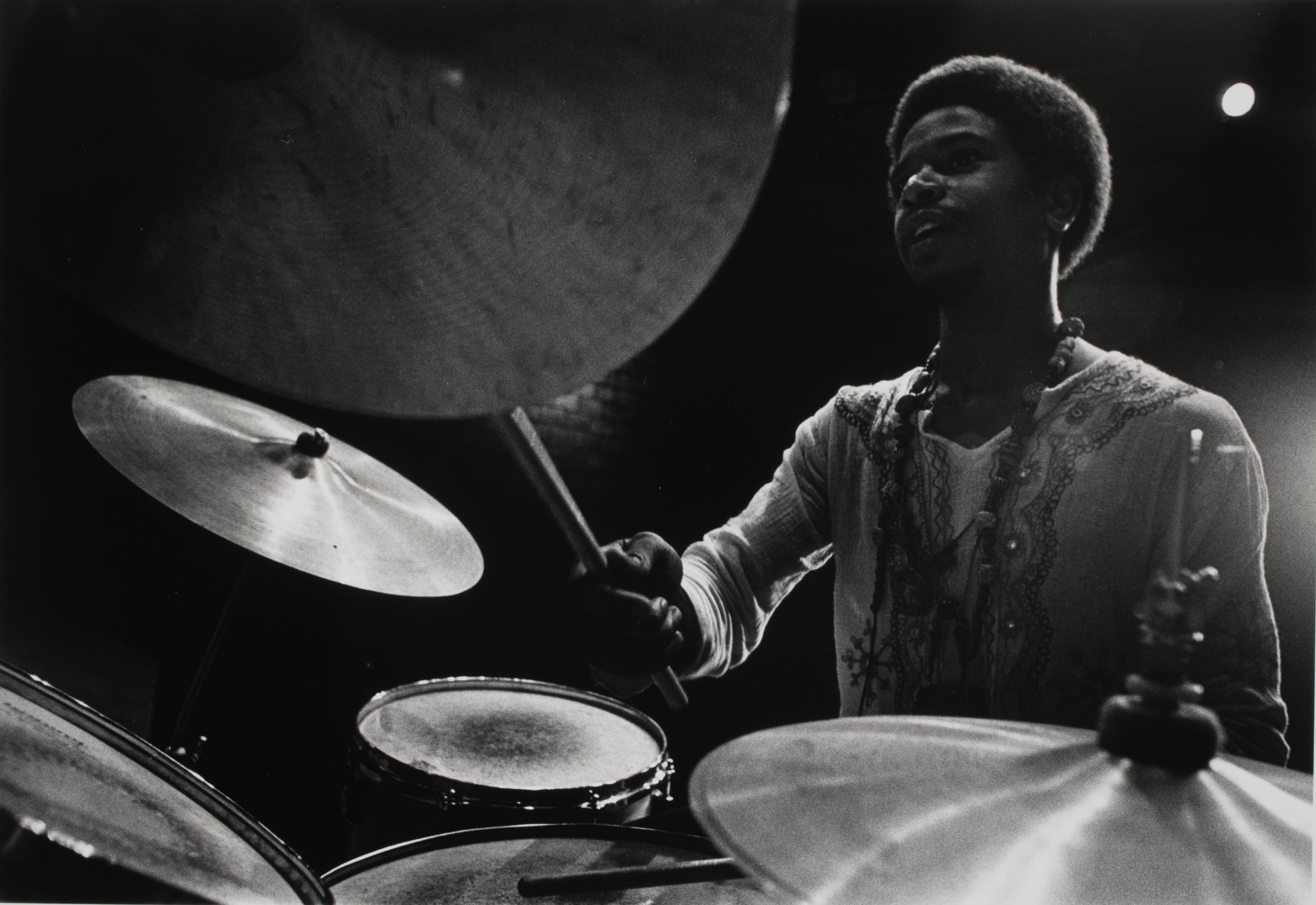 Dynamic close-up view of a Black 1970s drummer taken from between two cymbals.
