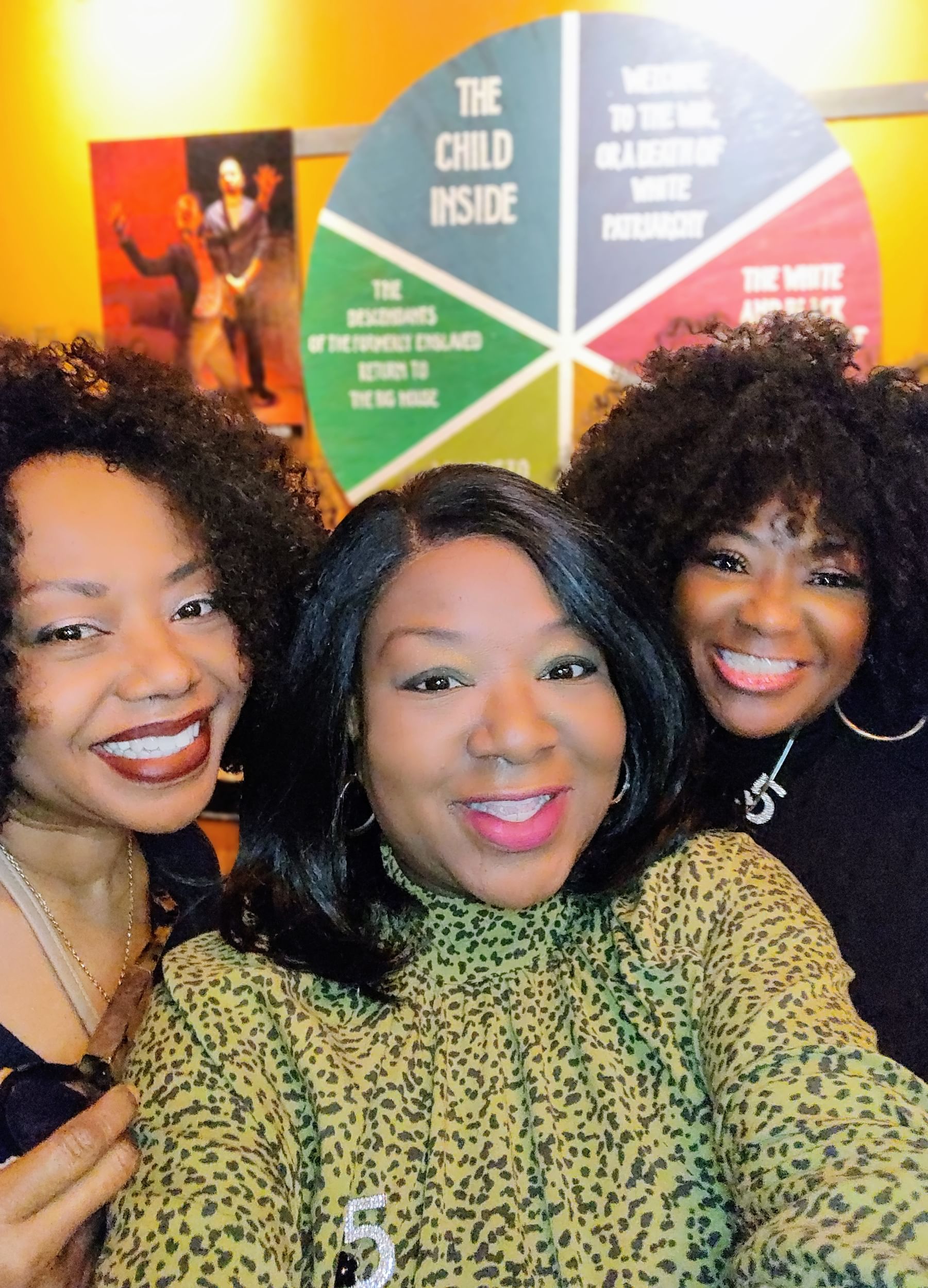 Close-up on three Black women in opening-night outfits smiling together.