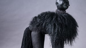 A figure made with black fabrics has four legs, hair, and a tail that gives it a poodle shape, but a human like head