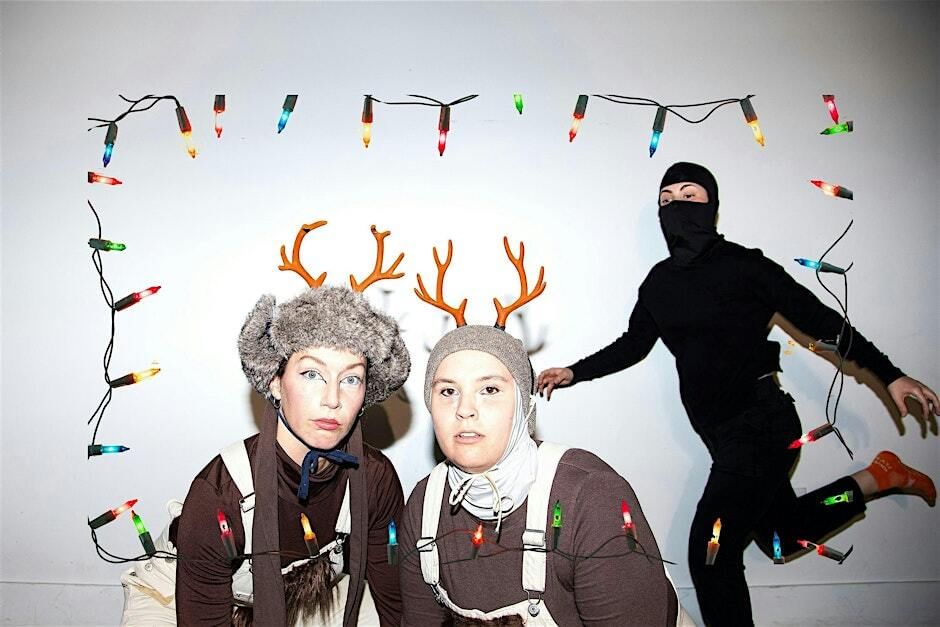 Two people wear reindeer hats. Holiday lights surround the photo frame. A person dressed in black dances in the background