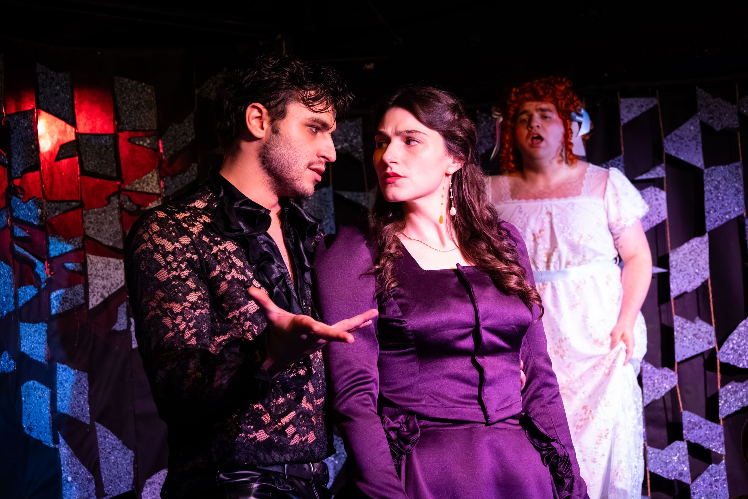 Carter, in a sexy black lace shirt, speaks to Silano, who wears a satiny purple dress and looks perturbed.