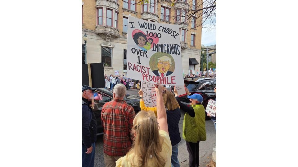 Close-up on a hand-illustrated protest sign that says “I would choose 1,000 immigrants over 1 racist pedophile.”