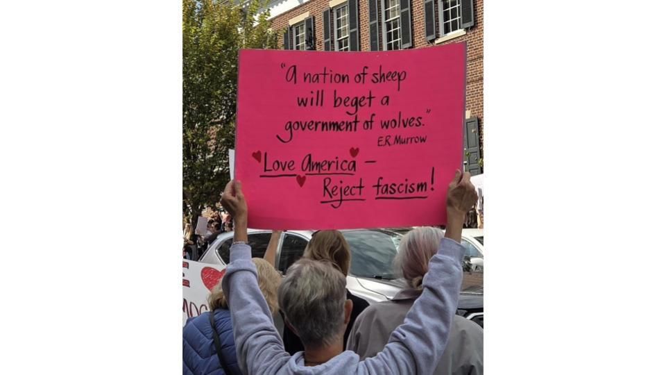 Close-up on a sign quoting E.R. Murrow: A nation of sheep will beget a gov’t of wolves and adds Love America, reject fascism!