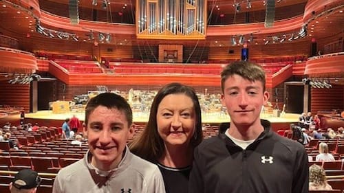 Ykoruk stands between her teenage sons in the aisle of the theater, all smiling. A huge organ is behind them above the stage.