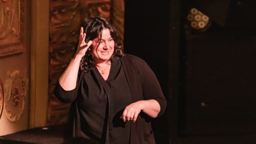 Close-up on McGarry, a white woman wearing black, signing during the show.
