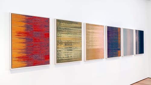 Receding from the left on a white wall, six colorful square panels depicting what looks like visible sound vibrations.