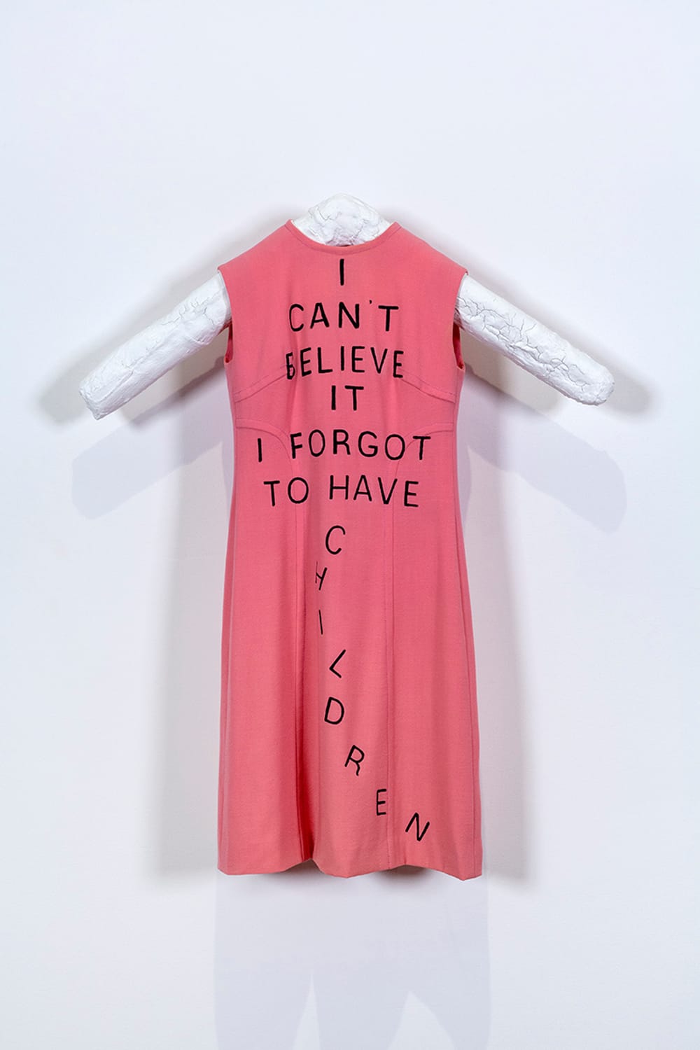 Vintage sleeveless pink dress with the artwork title written on it in large black block lettering.
