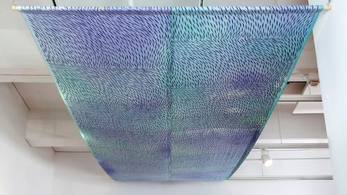 View from beneath hanging fabric with a soothing pattern like small birds or fish moving together on a blue field