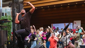 A dancer on stage moves in front of a crowd, many of which also seem to be dancing and moving and enjoying the show
