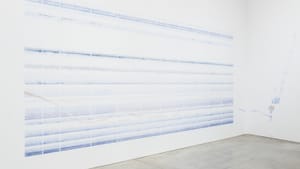 A view of the PMA installation of Tanya Goel’s Index 2015/2020. Strips of faint blue on the wall rise taller than a person