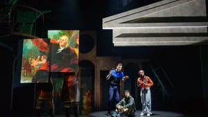 At right Orr explains something to Alburo & Wilson, looking outward. At left, actors hold panels with a painting of Franklin